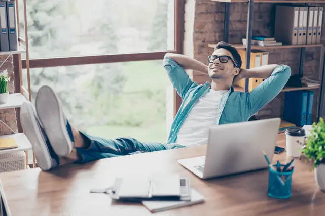 Man relaxing at desk with laptop